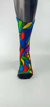 Load image into Gallery viewer, A stylistic bamboo sock with flowing whimsical designs in yellow, purple, blue, black, and red shapes.
