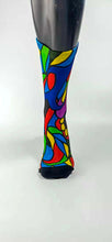 Load image into Gallery viewer, A stylistic bamboo sock with flowing whimsical designs in yellow, purple, blue, black, and red shapes.